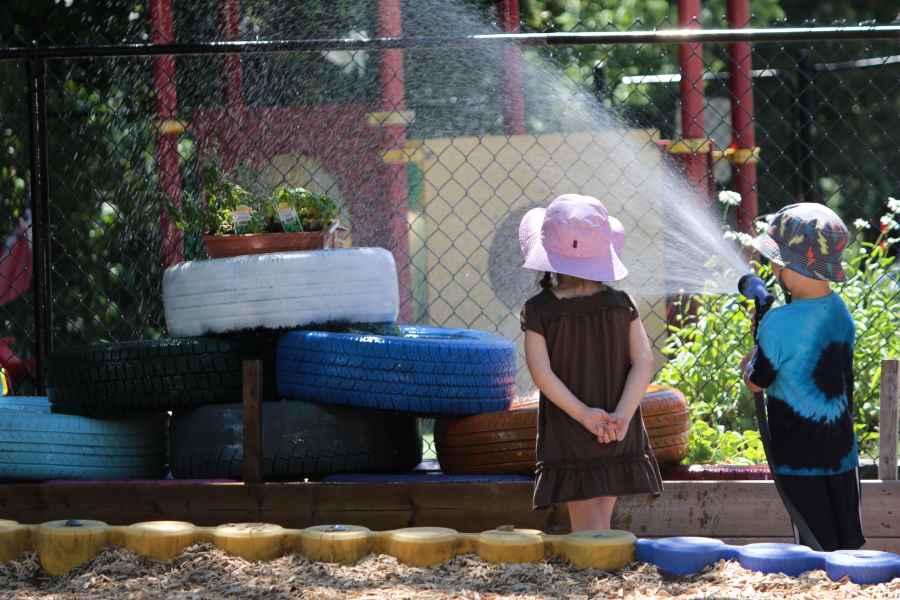boy watering plants as a girl watches